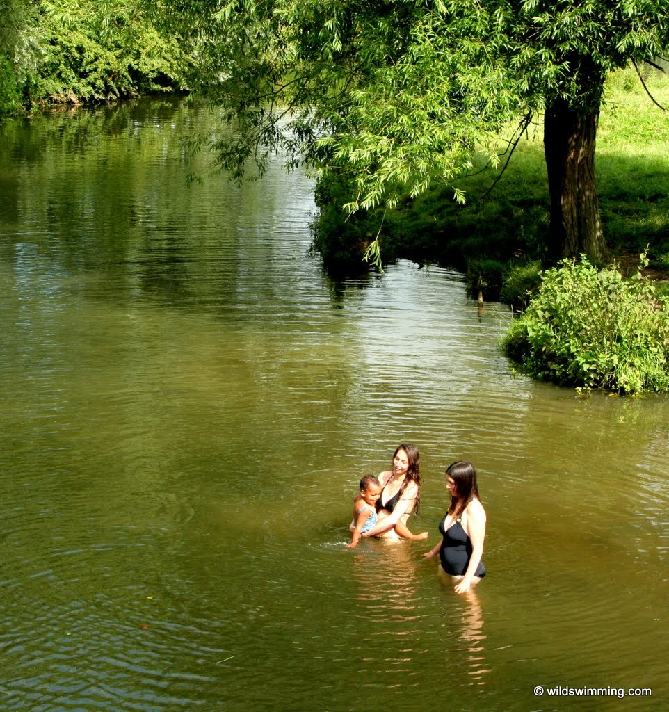 Two women with a child in the waters of Fen Bridge at Dedham Vale