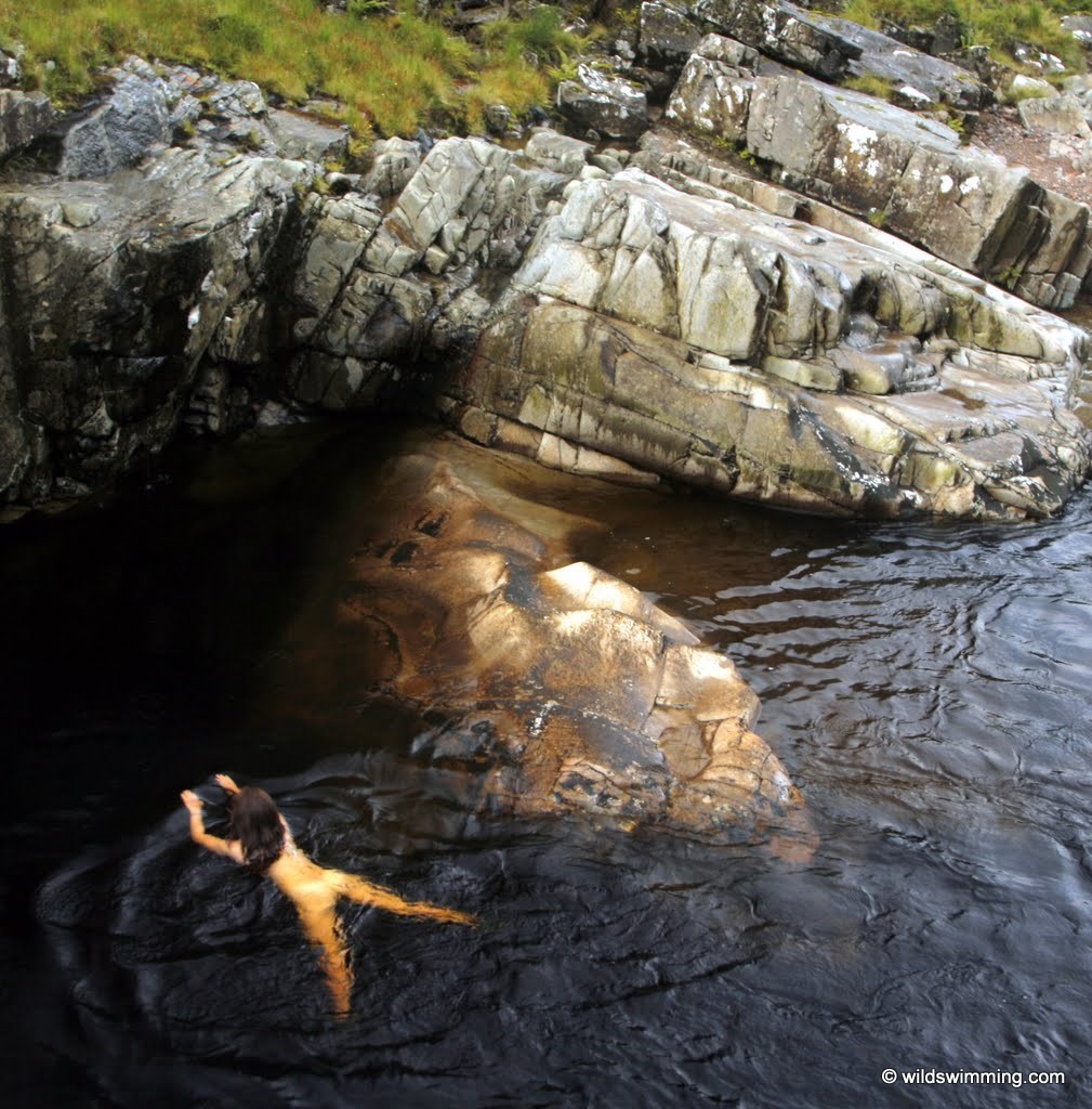 **Corrected grammar:**  A woman swimming in a river canyon at **Lower Glen Etive**.